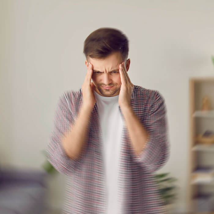 Man standing in living room, experiencing vertigo