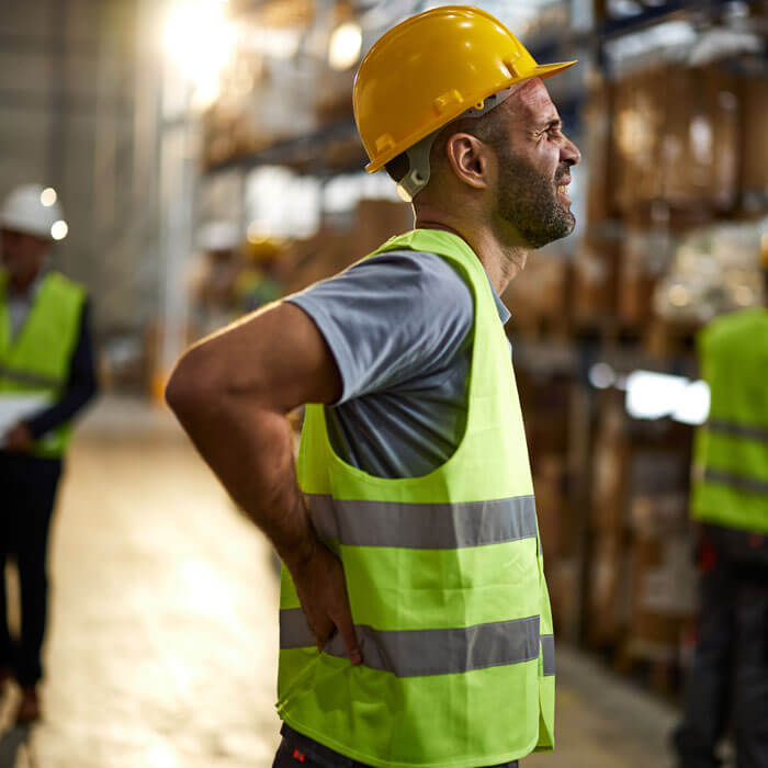 worker holding his back in pain at distribution warehouse